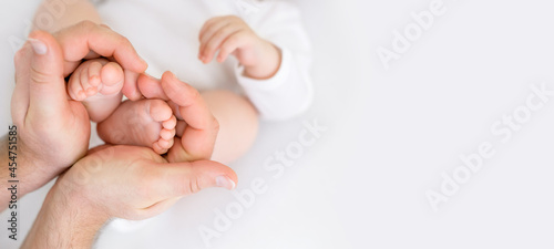 Small newborn baby legs in the shape of a heart in dad's strong male hands. Tenderness and love from birth. Care and raising of children health. banner