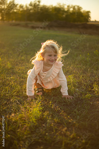 A girl with long hair plays and runs in the rays of the setting sun in a pink dress