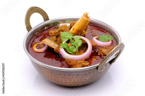 Indian style mutton curry in a copper brass bowl on white background