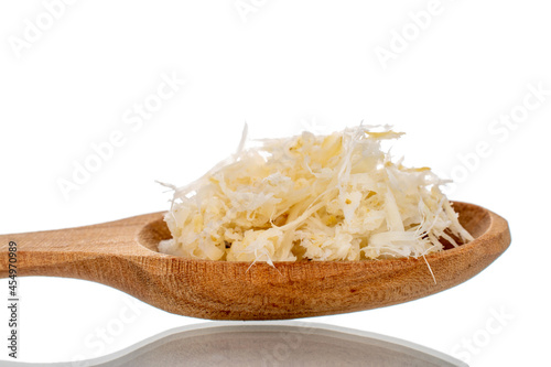 Grated horseradish root with a wooden spoon, close-up, isolated on white.