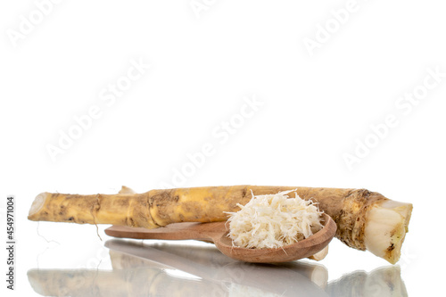 One whole spicy horseradish root and grated with a wooden spoon, close-up, isolated on white.