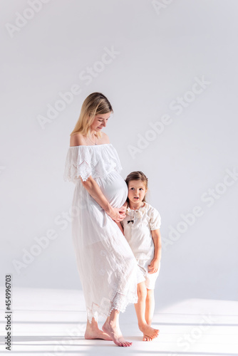 Little girl kisses hugs pregnant mother on an isolated white background. Healthy pregnancy woman