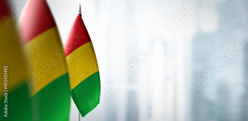 Small flags of Guinea on a blurry background of the city
