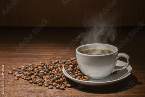 white cup of hot coffee with smoke with coffee beans and sackcloth full of coffee beans with rope