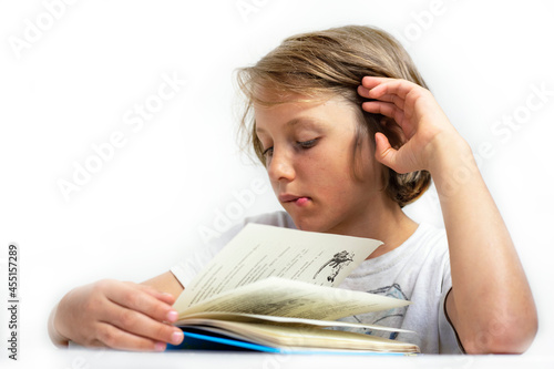 attentive boy reads an interesting book on a white background, back to school, education.