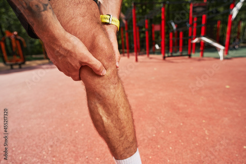 Sportsman touching his knee during workout outdoors