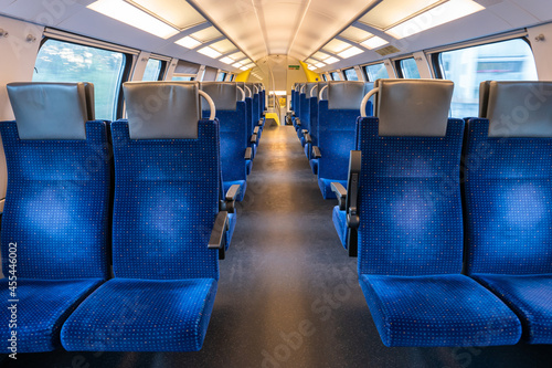 Empty blue seats inside train cabin, corridor view, no people.