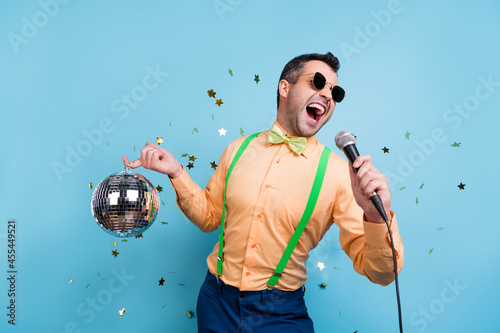 Photo of funny brunet young man sing hold ball wear eyewear peach shirt spectacles isolated on blue color background