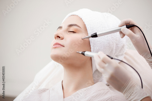 Young woman having micro current galvanic facial treatment with electrodes for lifting face. Concept preventing acne and oily skin problems