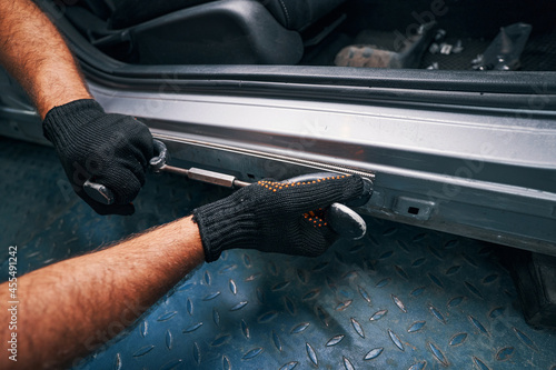 Person holding straightening tool pressed to car side door frame