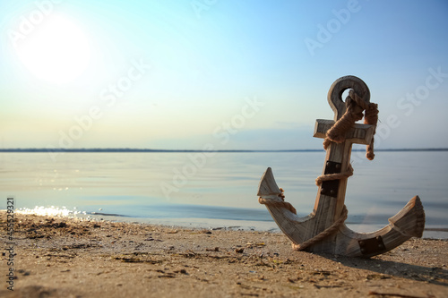 Wooden anchor on river shore near water
