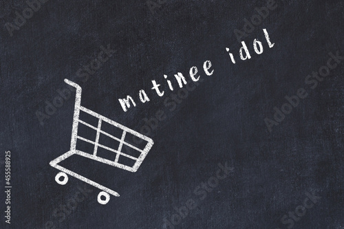 Chalk drawing of shopping cart and word matinee idol on black chalboard. Concept of globalization and mass consuming