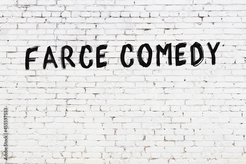 Inscription farce comedy painted on white brick wall