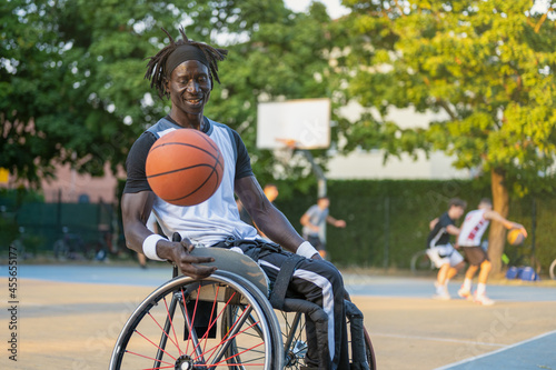 African man with a disability caused by polio playing basketball, champion athlete having disability in a wheelchair, concept of determination and mental toughness