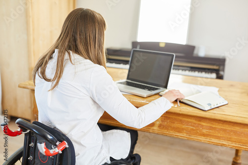 Woman in a wheelchair with paraplegia works on the laptop