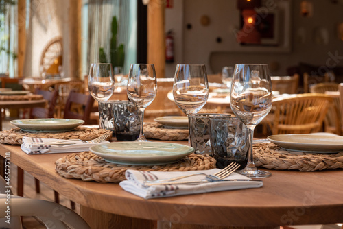 Mesa de restaurante turístico en la playa con copas, vasos, platos y cubertería completa