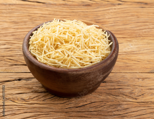 Potato straw or shoestring potato in a bowl over wooden table