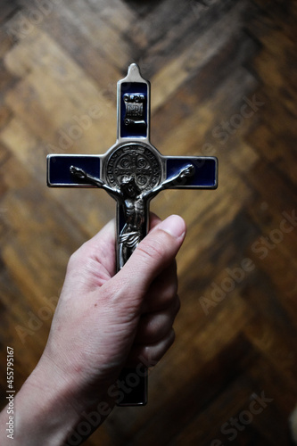 Krzyżyk z medalikiem św. Benedykta zaciśnięty w dłoni