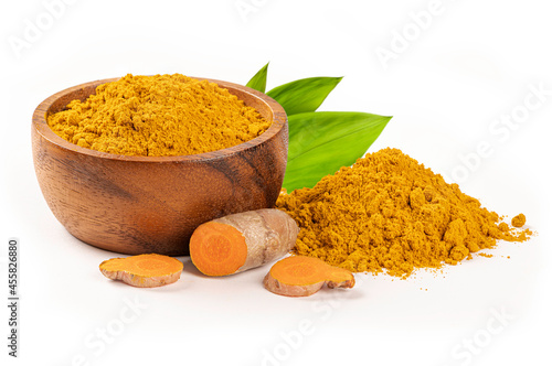 Turmeric powder in wooden bowl with turmeric sliced and leaves on white background.