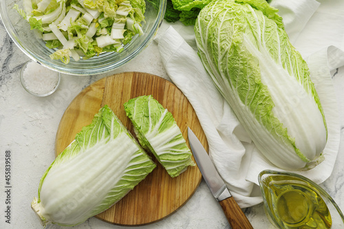 Board with fresh chinese cabbage on light background