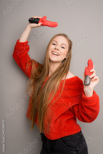 Sex toys in the hands of an attractive long-haired girl.Red dildo and dildo.Useful for sex shops