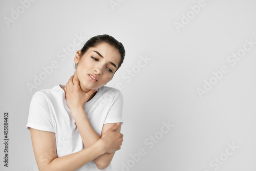 brunette in a white t-shirt pain in the neck light background