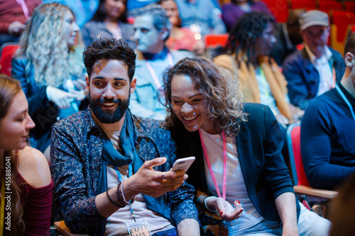 Man and woman with smart phone in conference audience