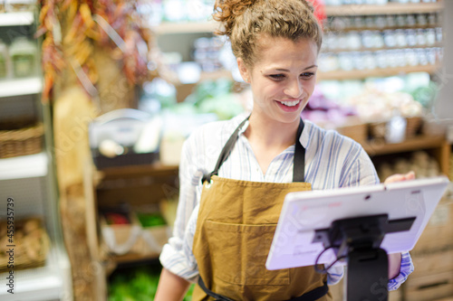 Female cashier using touch screen cash register in grocery store