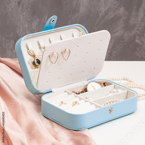 Open blue jewelry box with accessories on gray background. Storage system for women's jewelry