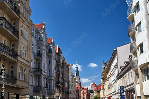 street with facades of historic tenement houses and the tower of the town hall