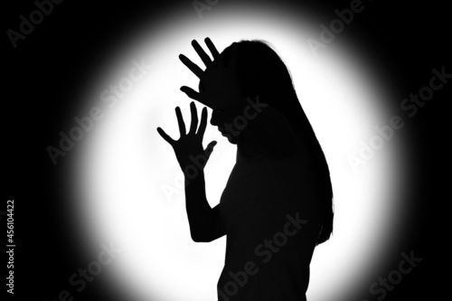 Silhouette of scared young woman on dark background. Concept of harassment