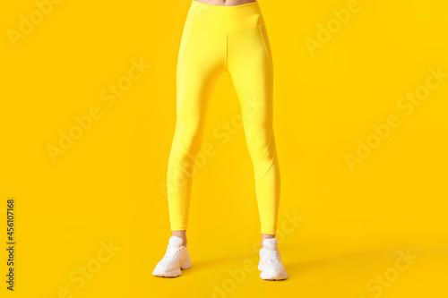 Legs of sporty young woman in leggings on color background