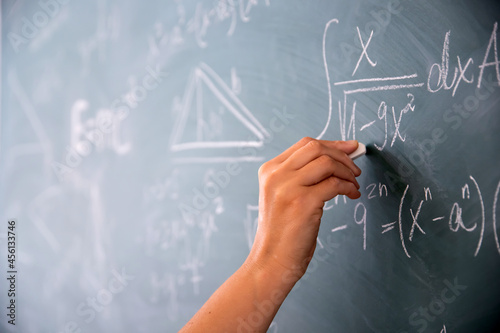 Teacher or student writing on blackboard during math lesson in school classroom