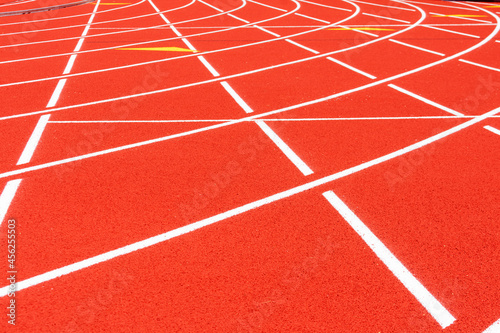 All-weather running track. White solid lines crosses on red rubber racetracks, selective focus. Racing curve on runner lanes surface