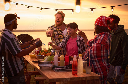 Young people eating fast food at the table during a beach party outdoors