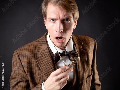 A young man in the image of a Victorian scientist, adjusts his glasses