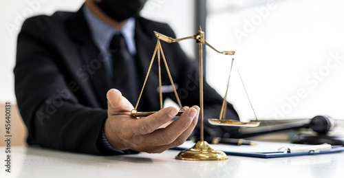 The male lawyer puts a second hand on the scales of justice on his desk, stating that the matter must be justified and not contrary to law and humanity. The concept of legal jurisprudence.