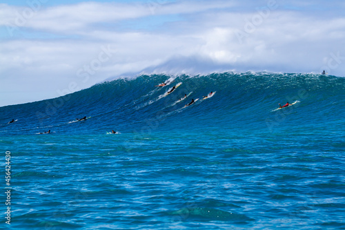 Surfers paddling over a giant wave