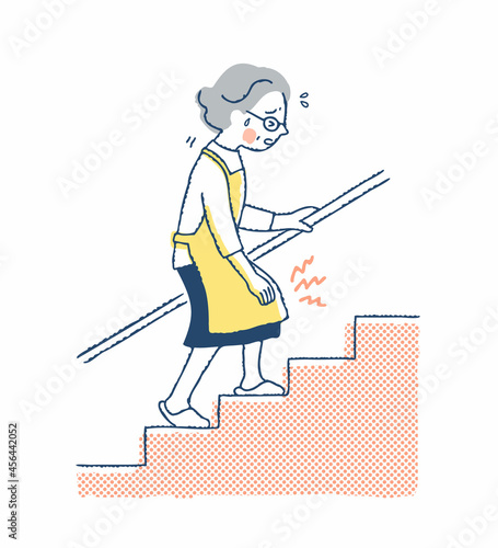 膝の痛みを我慢しながら階段を上る女性