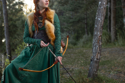 Beautiful red-haired girl-archer of Middle Ages in outdoor. Fantastic concept