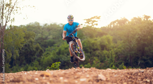 Mountain bikes cyclist cycling, Asian man athlete riding biking jumping on rocky terrain trail, extreme sport wear gear uniform helmet, exciting freedom outdoor sunset nature healthy active lifestyle