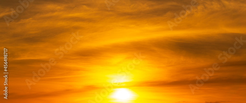 The rising sun shines brightly in the orange sky.