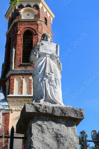 KLECZA DOLNA, POLAND - SEPTEMBER 11, 2021: A stone figure of an angel in front of the entrance to the Church of st. Lawrence Martyr in Klecza Dolna, Poland.