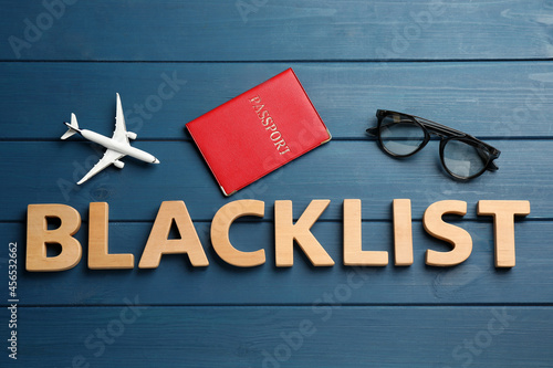 Word Blacklist of letters, toy airplane and passport on blue wooden background, flat lay