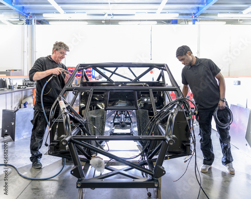 Engineers working on racing car in racing car factory