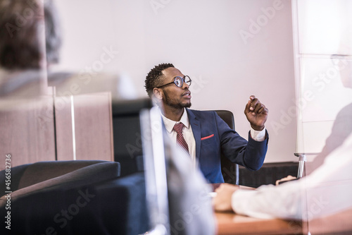 Window view of businessman questioning in board meeting