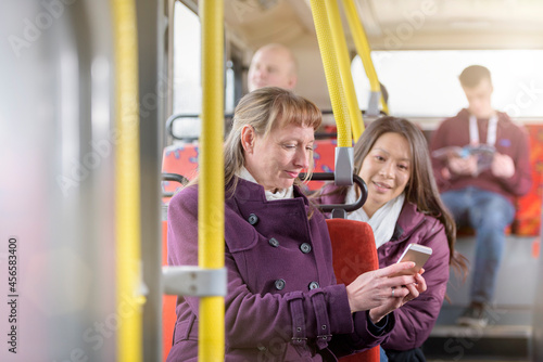 Passengers looking at smartphone on electric bus