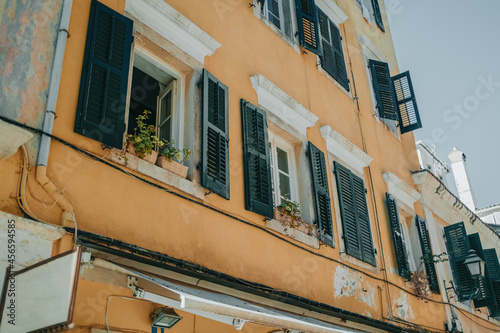 Medieval buildings in Greece island. Photo of local apartment building on streets in Corfu, Kerkira. Windows with shutters. Facades of old houses. Traveling concept.
