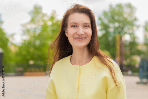 portrait of smiling pensive middle aged woman. elderly businesswoman near business center. lecturer, teacher at university, adult lady with smile in the city outdoors.