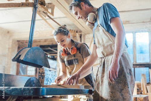 Team of carpenters working on details of a wood cut in their vintage workshop